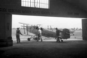 Egy Bücker Bü 131-es repülőgépet tolnak ki a bölcs feliratú hangárból, 1949., forrás: Fortepan