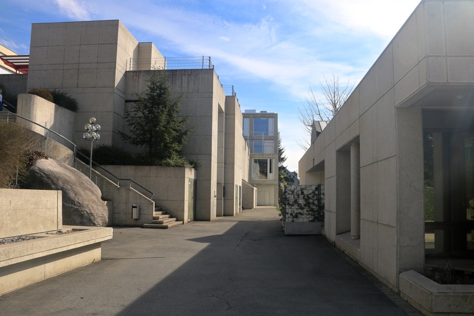 A meglévő, teraszos kialakítású iskolaépület szomszédságába tervezett tornaterem, községháza és légoltalmi központ, Belmont-sur-Lausanne, Svájc, Guth Ferenc. Az együttes 2012–14-ben tovább bővült a 2b architectes tervei szerint. 