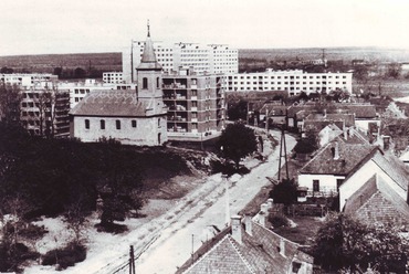 A Templomdomb alján futó Hideg utca az átépítés előtt, 1970 környékén, északi irányba nézve. Ma a helyén a Kossuth utcai panelsor áll. Háttérben a garzonházak tízemeletes tömbjei. / Ajkai Fotóklub 