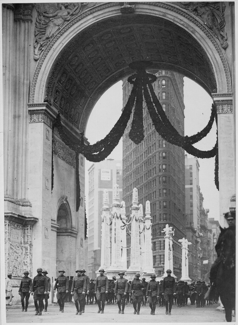 Az I. világháborús győzelem után a 165. gyalogezred felvonulása az akkor a Madison Square-en álló diadalív alatt, háttérben a Flatiron Building (1919). Forrás: Wikimedia Commons / Paul Thompson