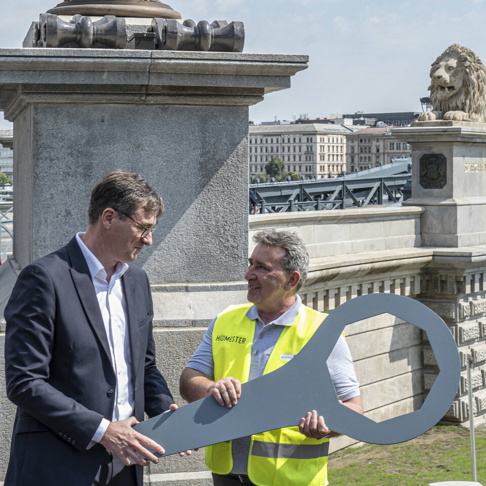 Karácsony Gergely főpolgármester (b) átadja a Lánchíd egyik csavarkulcsát Fazekas János hídmesternek a felújított híd átadásán a Lánchíd budai hídfőjénél 2023. augusztus 4-én.
