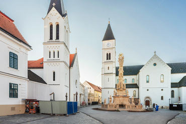 A vár legidősebb épületei közül több a Szentháromság-téren áll: balra a 18. század elején épült Szent István király templom, jobbra a középkori eredetű Szent Mihály-székesegyház. Mai neoromán formáját mindkettő a 20. század elejére nyerte el. Sárga homlokzatuk ezúttal hasonló, visszafogottabb színeket kapott.
