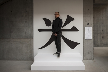 Taku Satoh, a kiállítás kurátora egy “rizs” írásjel részeként, fotó: Satoshi Asakawa