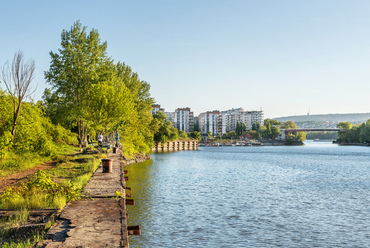 A vasúti híd vonalában, a Dunapart beépített területének mai, vadregényes határa, már nem a folyó főága, hanem az erdővel borított Népsziget, és az Újpesti öböl előtt.