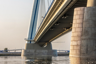 A Monostori híd részletes tervezése még 2007-ben kezdődött, a magyarországi Mátyássy László, és a szlovákiai Nagy László tervei alapján. A munka kezdetén a legfőbb nehézséget a két ország eltérő műszaki előírásai okozták.