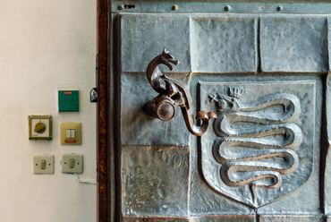 A hatalmas bronz kapu 1970-re készült el, Péri József ötvösművész munkája. Rajta belépve, a kapuőri szobában hamar az ötven évvel ezelőtti rekonstrukció jegyeit találjuk.