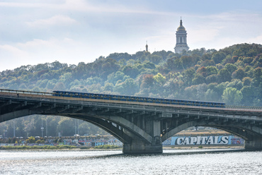 Az Arsenala állomás után a metró hatalmas, hat nyílású vasbeton ívhídon keresztezi a Dnyeper folyót, a híd oldalsó konzolain közúti sávokkal. 