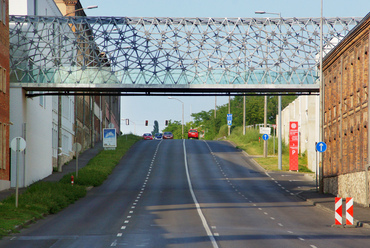 A Pécsi Zsolnay-negyed jelképe a terület két részét összekapcsoló gyalogoshíd, amely 2010 óta ível át a 6-os főúton. Építész tervezője a kulturális negyedért is felelős Herczeg László.
