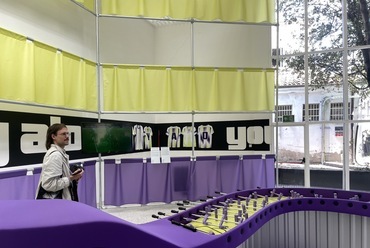 A pavilon centrumában egy hullámzó, hosszú csocsóasztal, ahol minden játékos egy oldalon áll. Kipróbáltuk, játszható a közös csocsó, nem túl élvezetes, ugyanis a (diverzitás jegyében) minden egyes bábú eltérő tömegű és méretű, így nehéz rúgni velük. 
